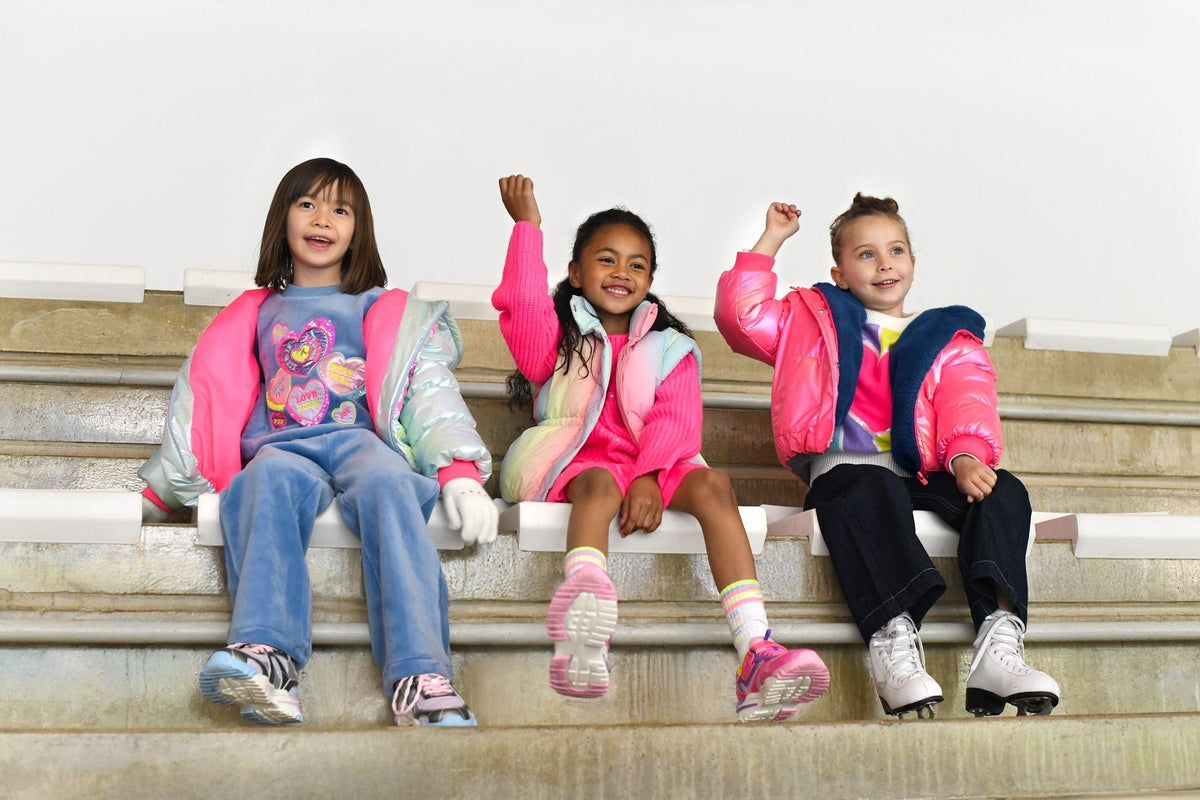Meisjes in kleurrijke Billieblush winterkleding op een bank — meisjeskleding winter 2026 bij Niñoz Almere