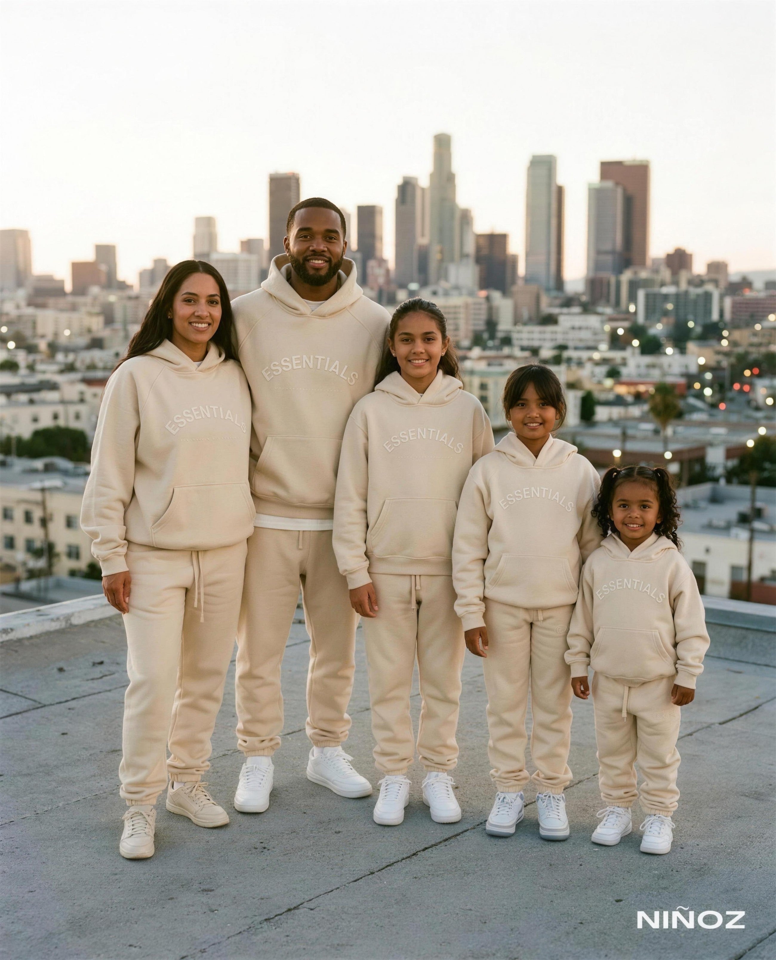 Gezin van vijf in matching beige Essentials Cou7ure hoodies met skyline op de achtergrond — Niñoz Almere