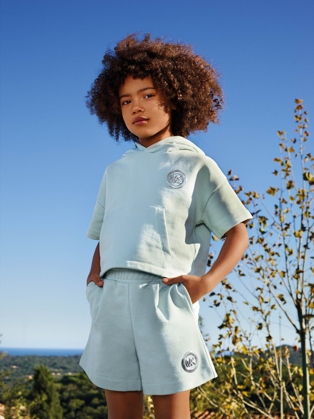 Kind in lichtblauwe Michael Kors zomerset in de zon — lente/zomer 2026 collectie bij Niñoz Almere