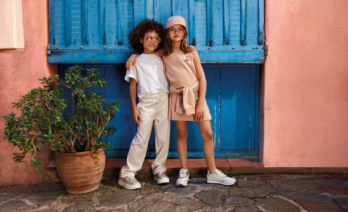 Sale babykleding — twee jonge kinderen in Michael Kors lente-outfits bij Niñoz