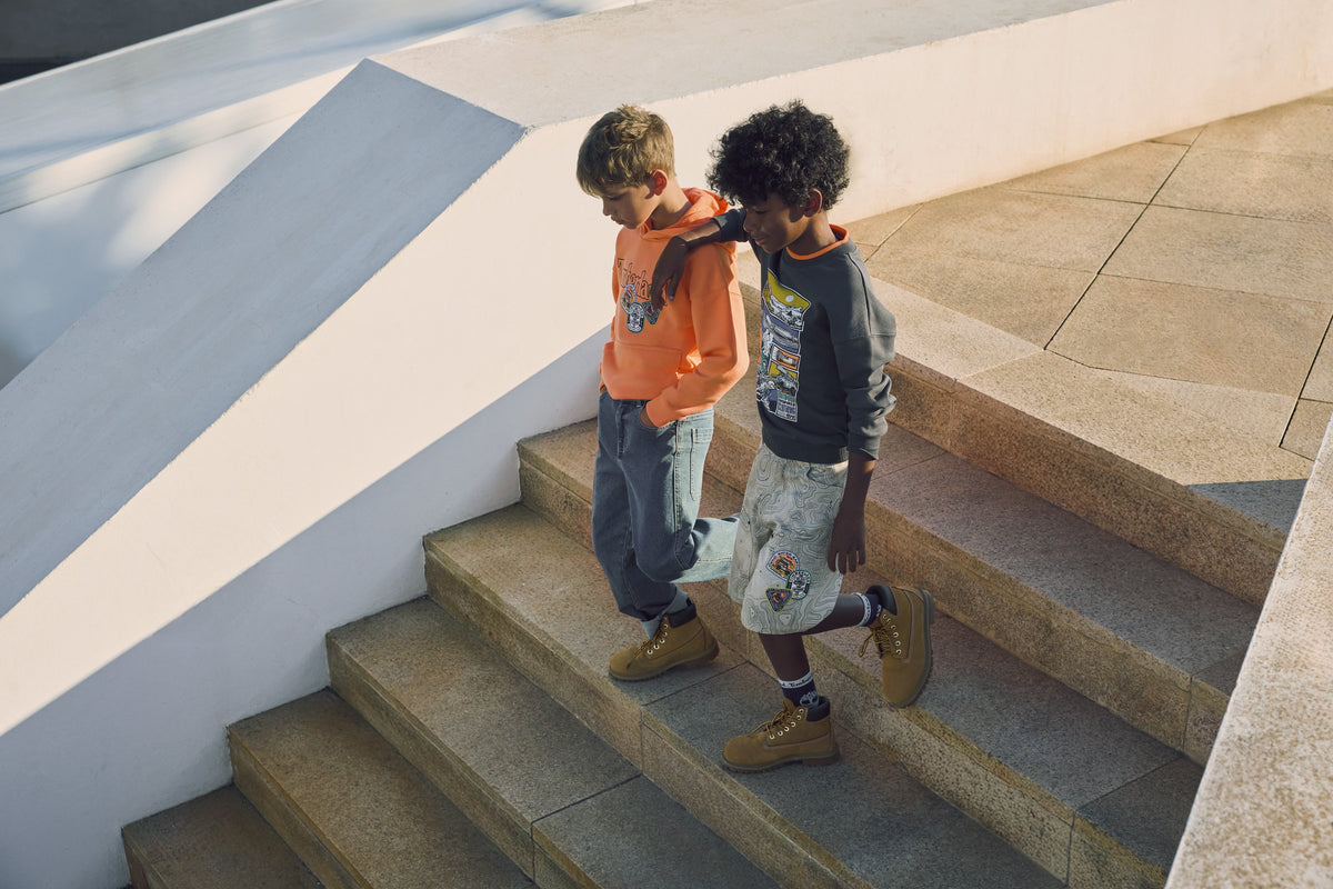 Sale jongenskleding — twee jongens op trap in Timberland lente-outfits bij Niñoz