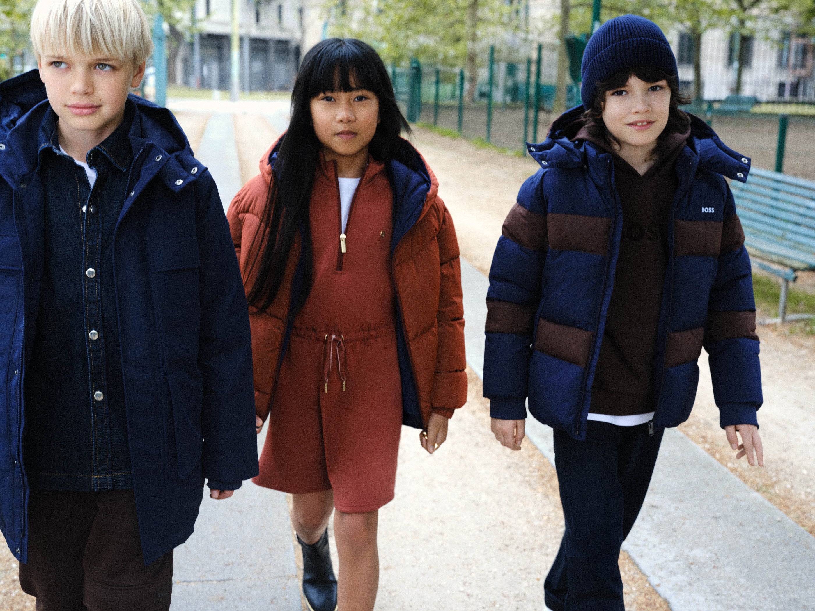 Drie kinderen in BOSS winterjassen lopen buiten — designer winterjassen voor kinderen bij Niñoz Almere