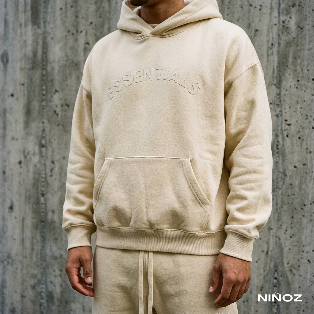Detail van de borstopdruk op een beige Essentials Cou7ure tracksuit — Niñoz Almere