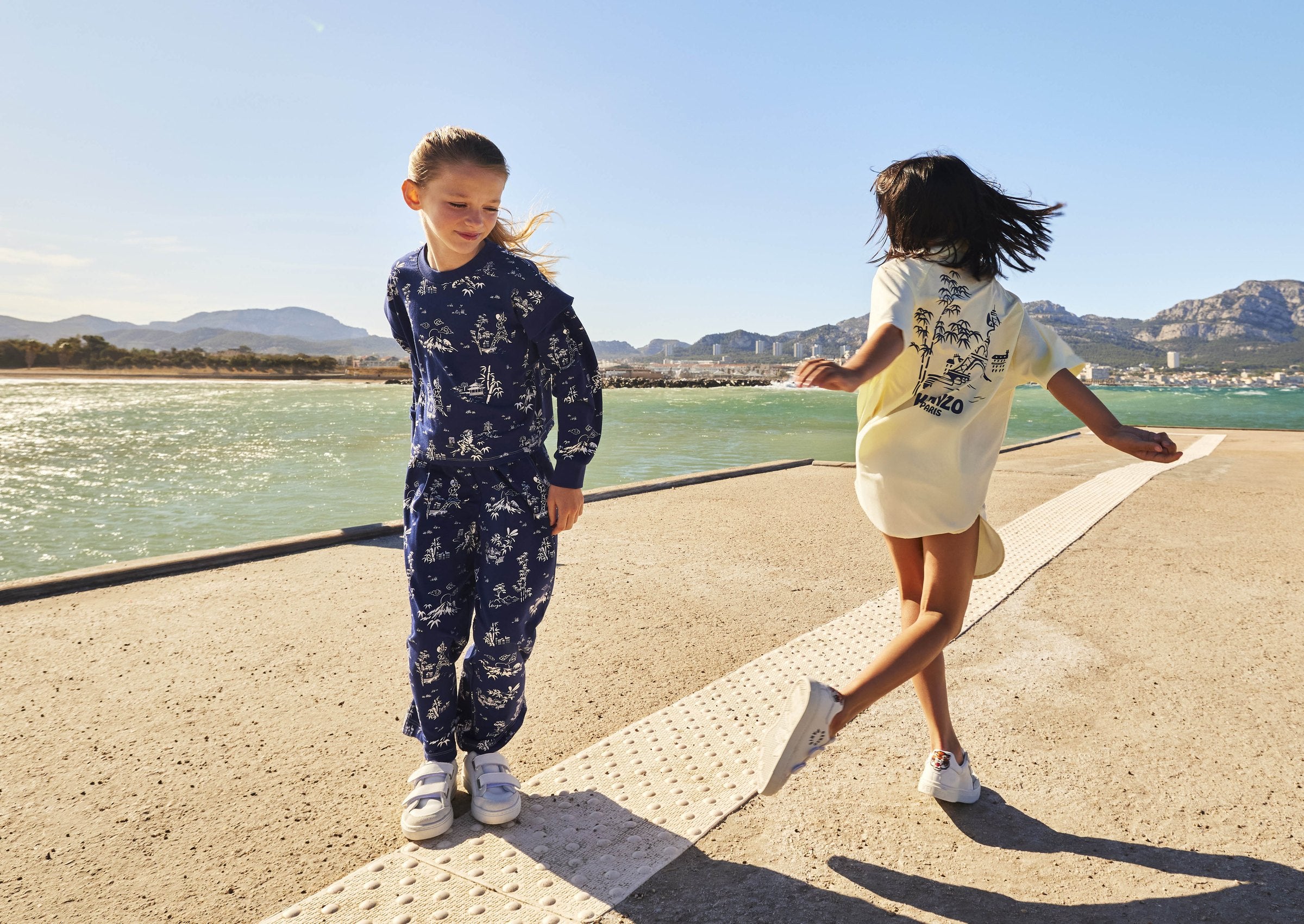 Meisje in witte Kenzo Kids jurk op een roze trap — designer kindermode bij Niñoz Almere