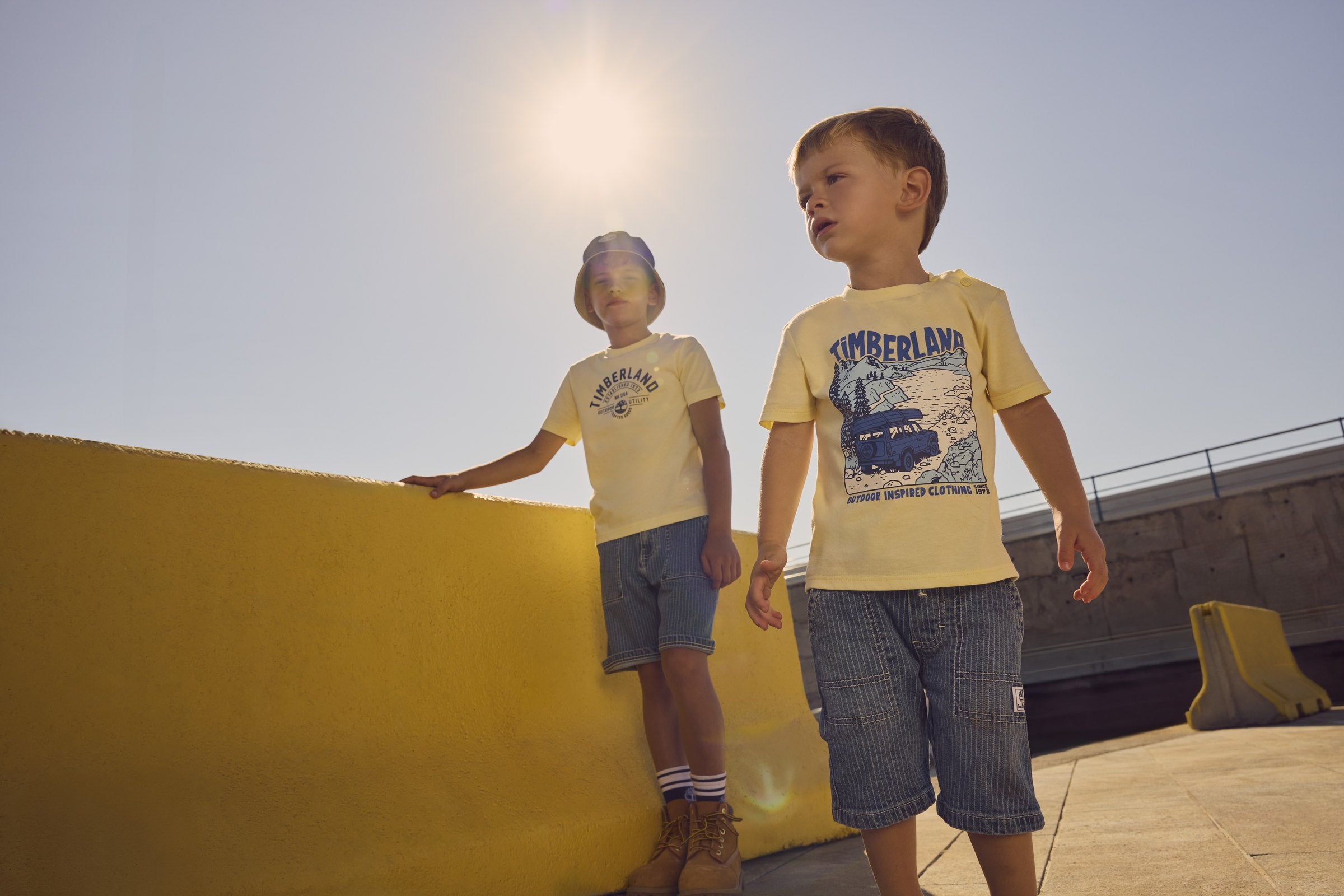 Twee jongens in gele Timberland T-shirts op een zonnig dak — jongenskleding bij Niñoz Almere